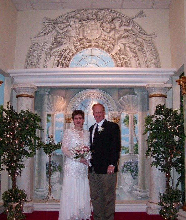 A couple at the chapel altar holding a lily bouquet