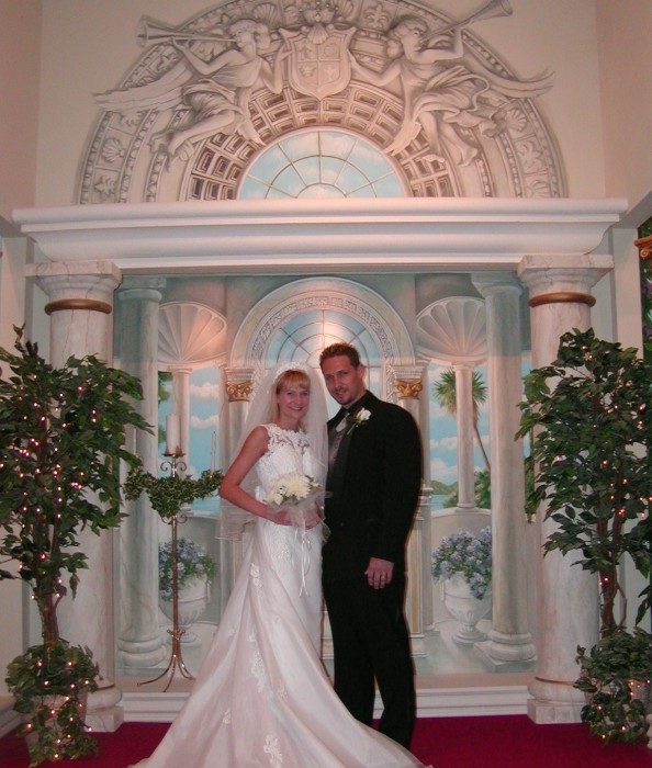 A bride in a long ivory train beside her groom