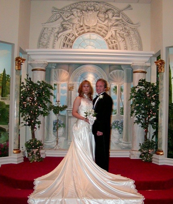 A bride in a long satin train in front of the chapel altar